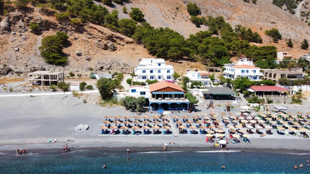 Agia Roumeli Hotel في أجيا روميلي: منظر جوي لشاطئ مع كراسي ومظلات