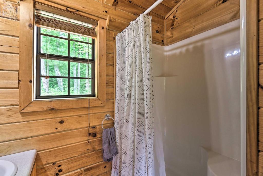 a bathroom with a shower curtain and a window at Quaint Log Cabin with Views Near West Jefferson in Warrensville
