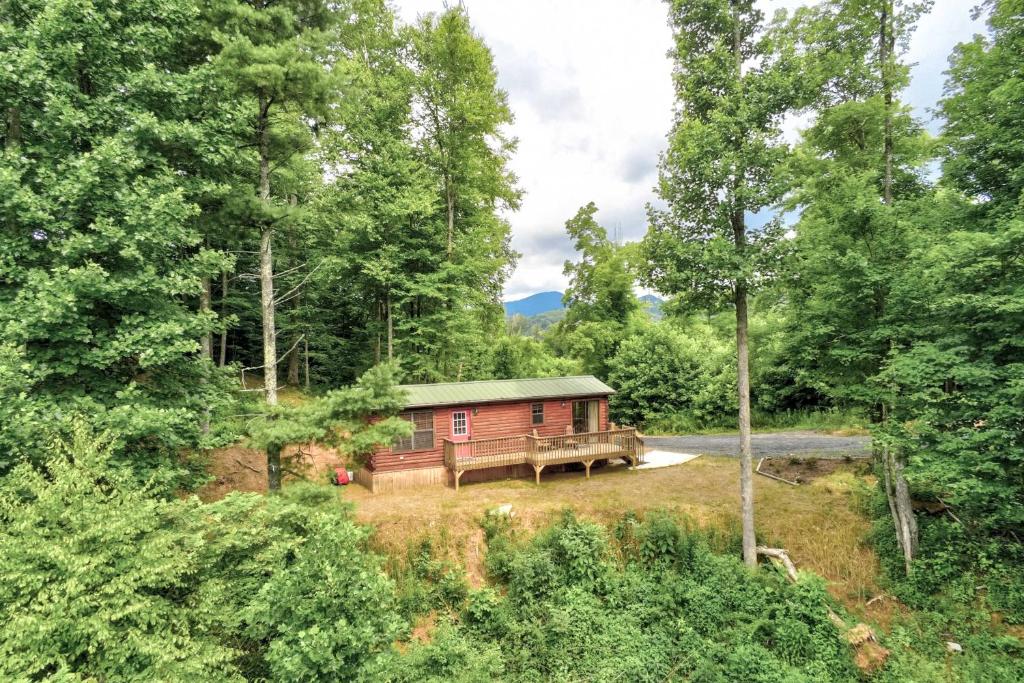 a small red cabin in the middle of a forest at Quaint Log Cabin with Views Near West Jefferson in Warrensville