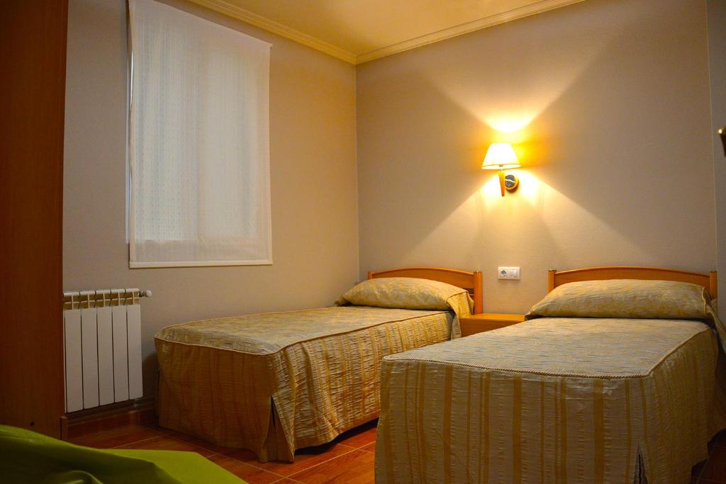 VimianzoにあるPensión Quilmesのベッド2台が備わる客室で、壁に照明が付いています。