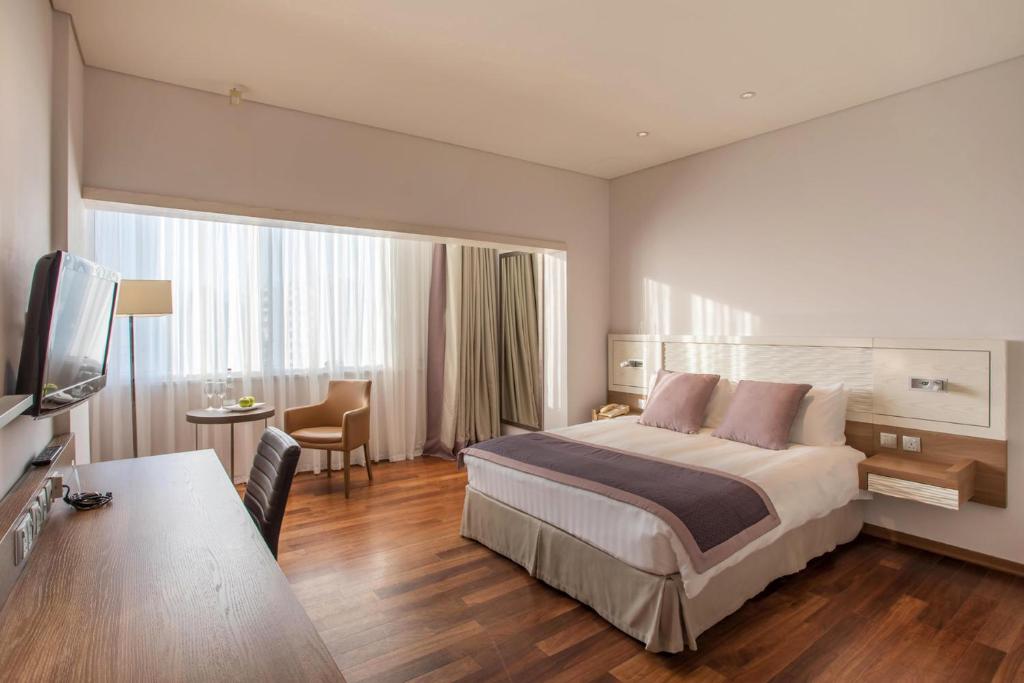 a hotel room with a large bed and a desk at Crowne Plaza Limassol by IHG in Limassol