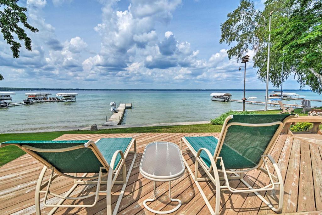 two chairs and a table on a deck overlooking the water at Higgins Lake House and Bunkhouse with Private Dock! in Roscommon