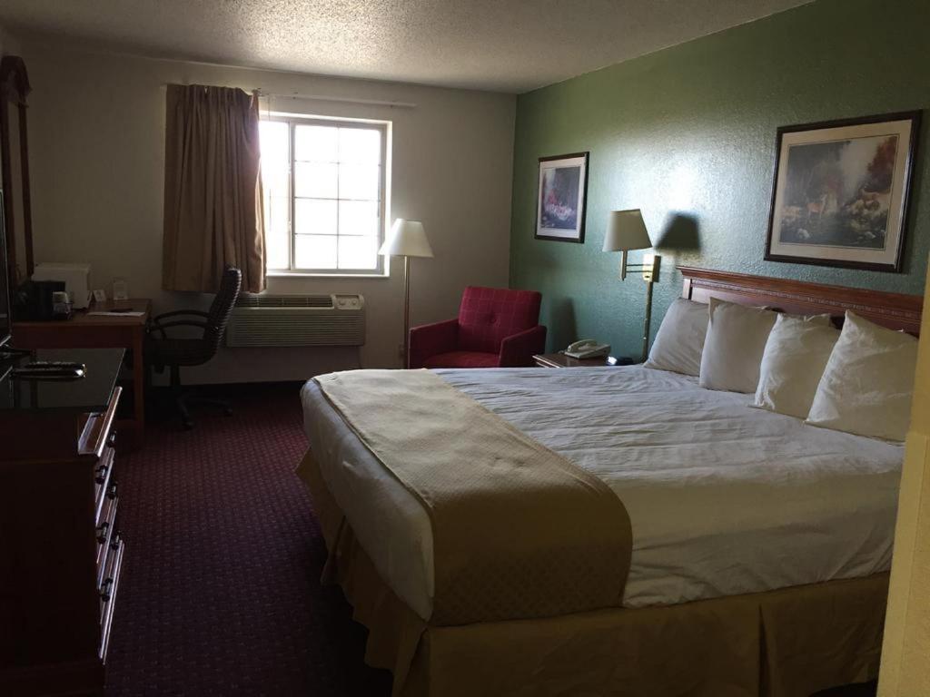 a hotel room with a bed and a chair and a window at Osceola Grand Hotel in Evart