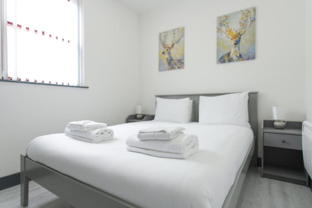 a bedroom with a white bed with towels on it at Nottingham City Centre Short Stay Apartments with Parking in Nottingham