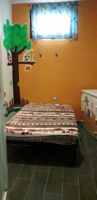 małe łóżko w pokoju z drzewem na ścianie w obiekcie Appartamento indipendente w mieście Santa Maria