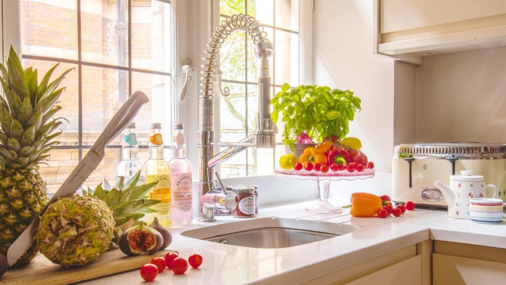 una cucina con lavandino e frutta e verdura sul bancone di Discover the Exclusive Charm of Covent Garden at a Luxury Nomads Home a Londra