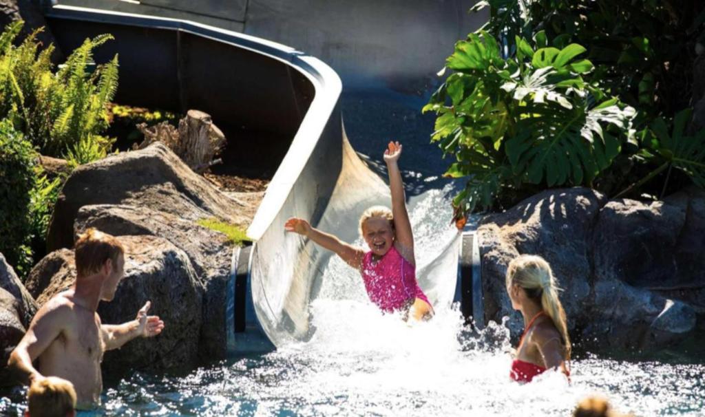 een klein meisje glijdt van een glijbaan in het water bij 1 BR Luxury Condo in Presitigious Honua Kai Resort #k430 in Lahaina