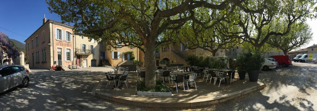 a group of tables and chairs under a tree at La salamandre in Venterol