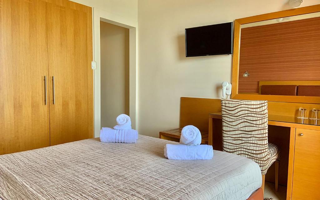 a bedroom with a bed with blue towels on it at Hotel Flisvos in Kalamata