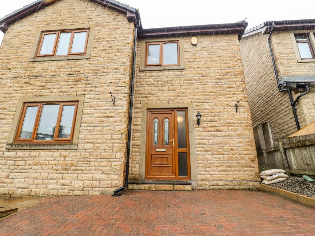 a brick house with a wooden door on a brick driveway at Rivendale in Colne