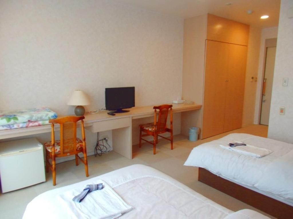 een kamer met 2 bedden en een bureau met een computer bij Sabi Katayama - Vacation STAY 56437v in Kaiyo