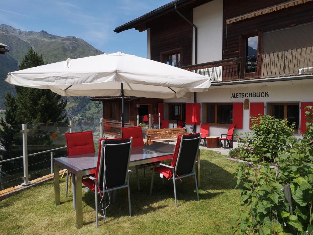 a table and chairs with an umbrella in front of a house at Aletschblick in Grächen