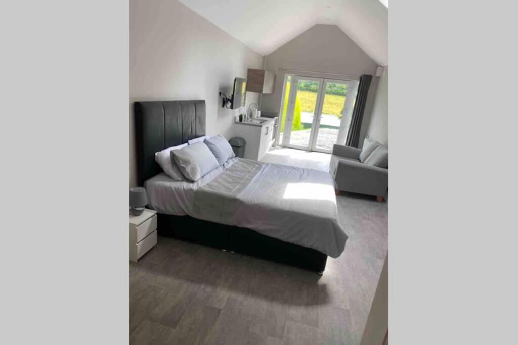 a bedroom with a large bed and a couch at The Forest Chalet - Stunning Studio Apartment in Ballycastle