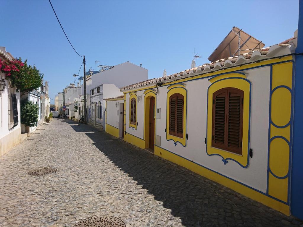 una calle con edificios amarillos y blancos en una calle empedrada en Cabanas de Tavira Unique, Luxury 2,5 bedroom House 50 meters to the water en Cabanas de Tavira