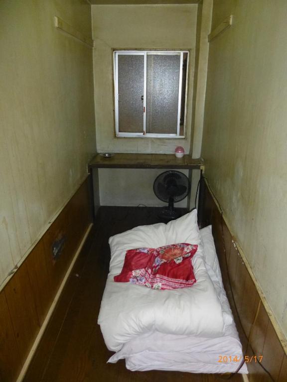 a small bed in a room with a window at Hotel Diamond in Osaka