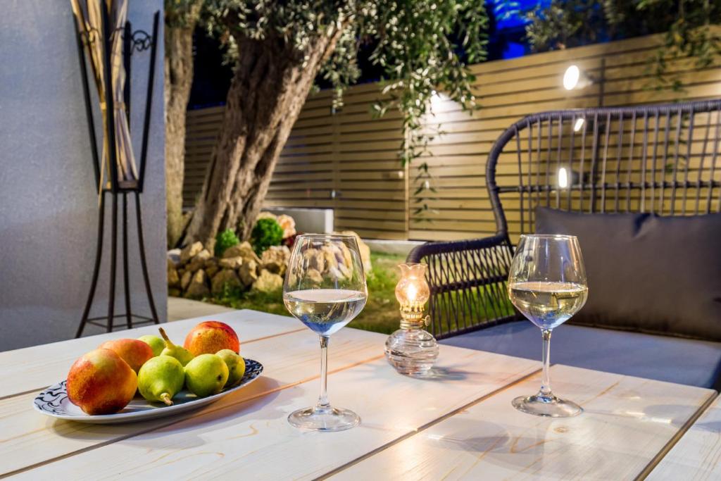 einen Tisch mit zwei Gläsern Wein und einem Obstteller in der Unterkunft Villa 4 you iliopetra in Skala Sotiros