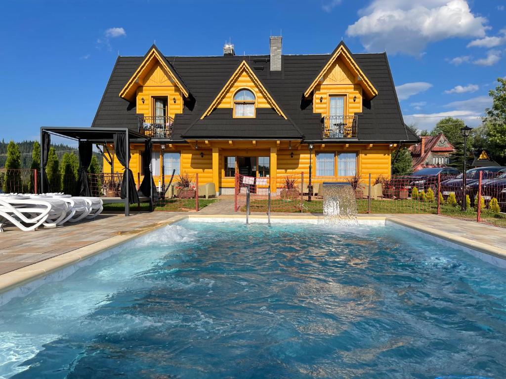 ein Haus mit einem Pool vor einem Haus in der Unterkunft Apartamenty Liliowe SPA & Wellness in Murzasichle