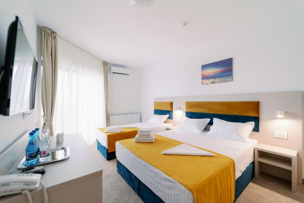 a hotel room with two beds and a tv at NOVUS Hotel in Eforie Nord