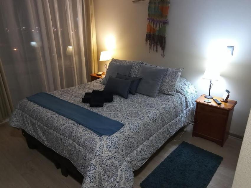 um quarto com uma cama grande com lençóis e almofadas azuis em depto nuevo temuco em Temuco