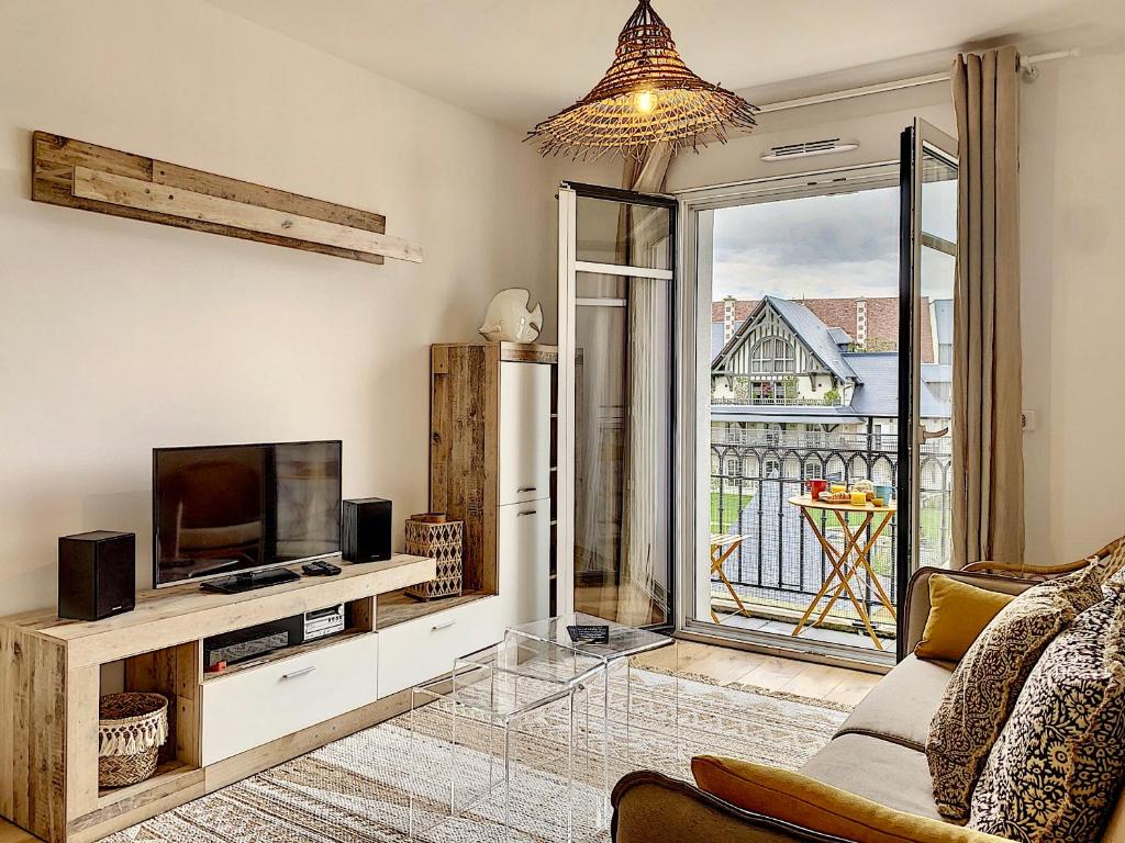 un salon avec une télévision et un canapé dans l'établissement L'ancre Marine YourHostHelper, à Deauville