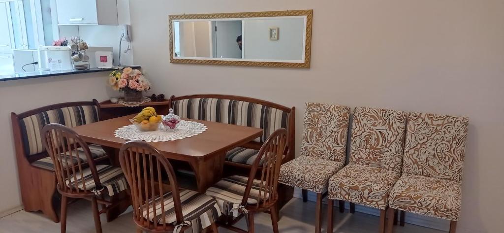 mesa de comedor con sillas y espejo en Apto Reali Fiori, en Campos do Jordão