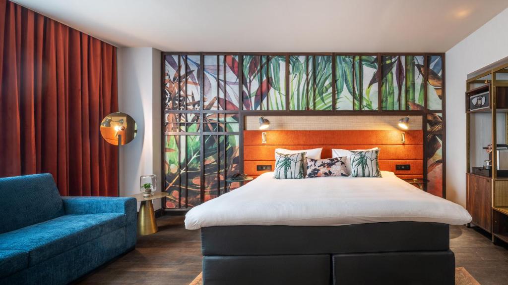 a bedroom with a large bed and a blue couch at Hotel Indigo Brussels - City by IHG in Brussels