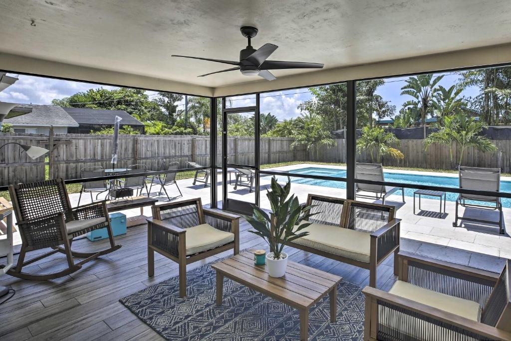 a patio with chairs and a pool with a ceiling fan at Chic Beach House with Lanai and Private Yard! in Naples