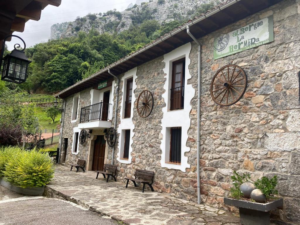 un edificio in pietra con panchine di fronte di Albergue La HERMIDA a La Hermida