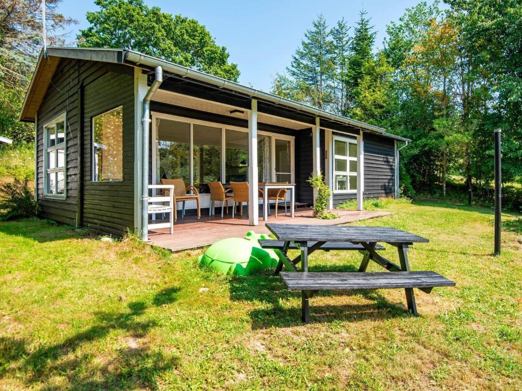eine grüne Hütte mit einem Picknicktisch im Hof in der Unterkunft 6 person holiday home in Knebel in Knebel