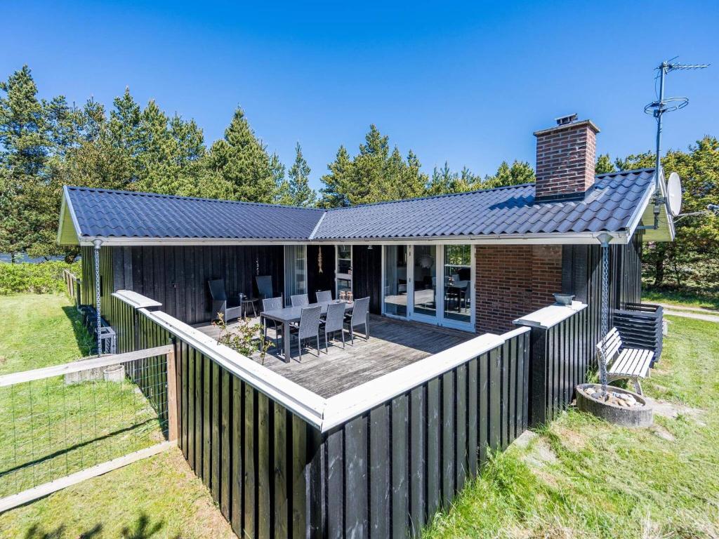 a small house with a wooden fence in a yard at Holiday home Nørre Nebel LXV in Nørre Nebel