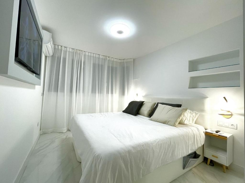 a white bedroom with a bed and a tv at Apartamento IMPERIO 2 - Marbella centro in Marbella
