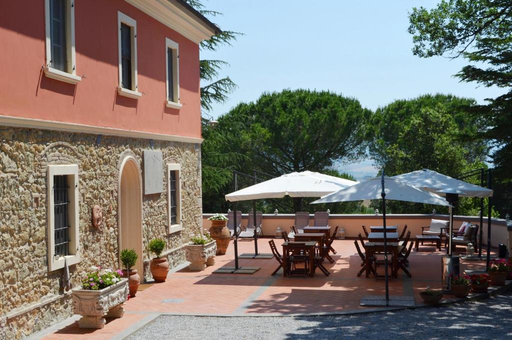 een patio met tafels en parasols naast een gebouw bij Agriturismo Terre della Rinascita in Castelnuovo della Misericordia