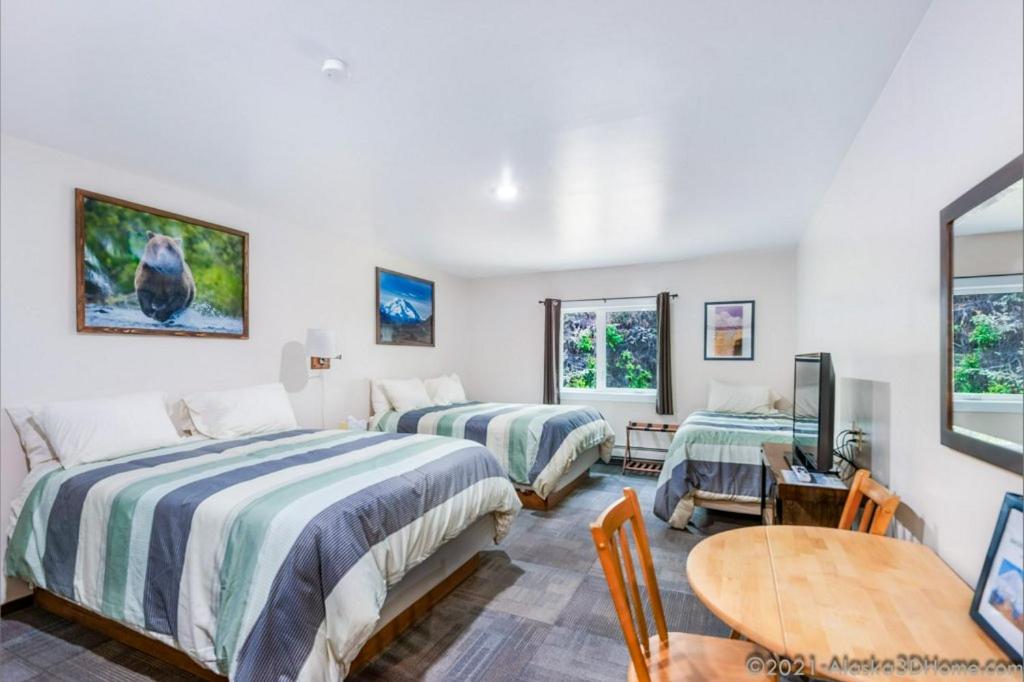a bedroom with two beds and a table and a desk at Backwoods Lodge in Cantwell