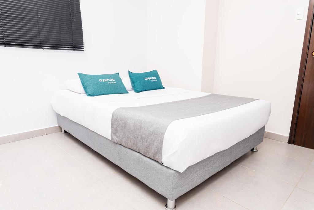 Una cama blanca con dos almohadas azules. en Ayenda Casa Prado 59, en Barranquilla