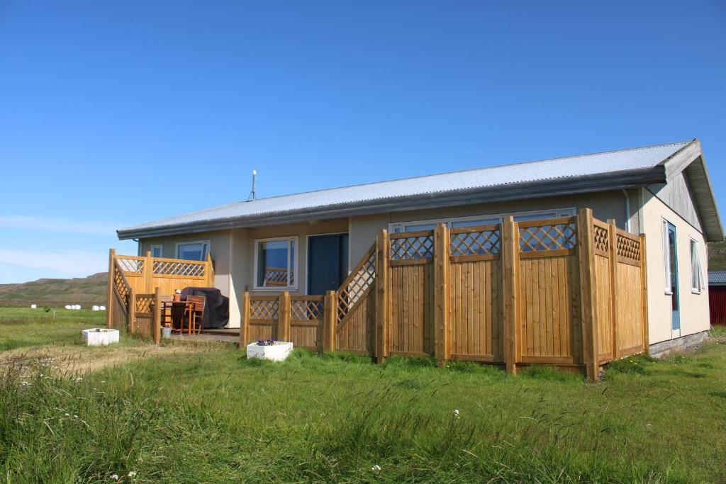 ein Haus mit einem Holzzaun und einem Hof in der Unterkunft Stóri-Bakki Guesthouse-with hot tub in Egilsstaðir