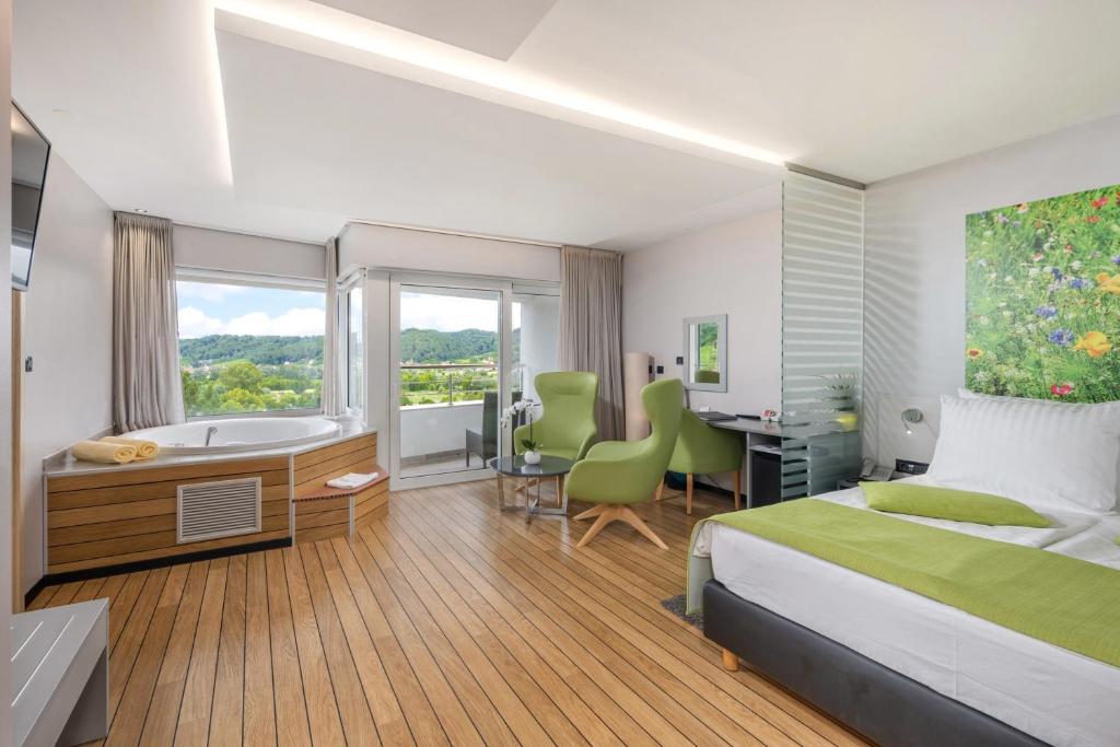 Schlafzimmer mit einem Bett, einem Schreibtisch und einer Badewanne in der Unterkunft Wellness Hotel Villa Magdalena in Krapinske Toplice