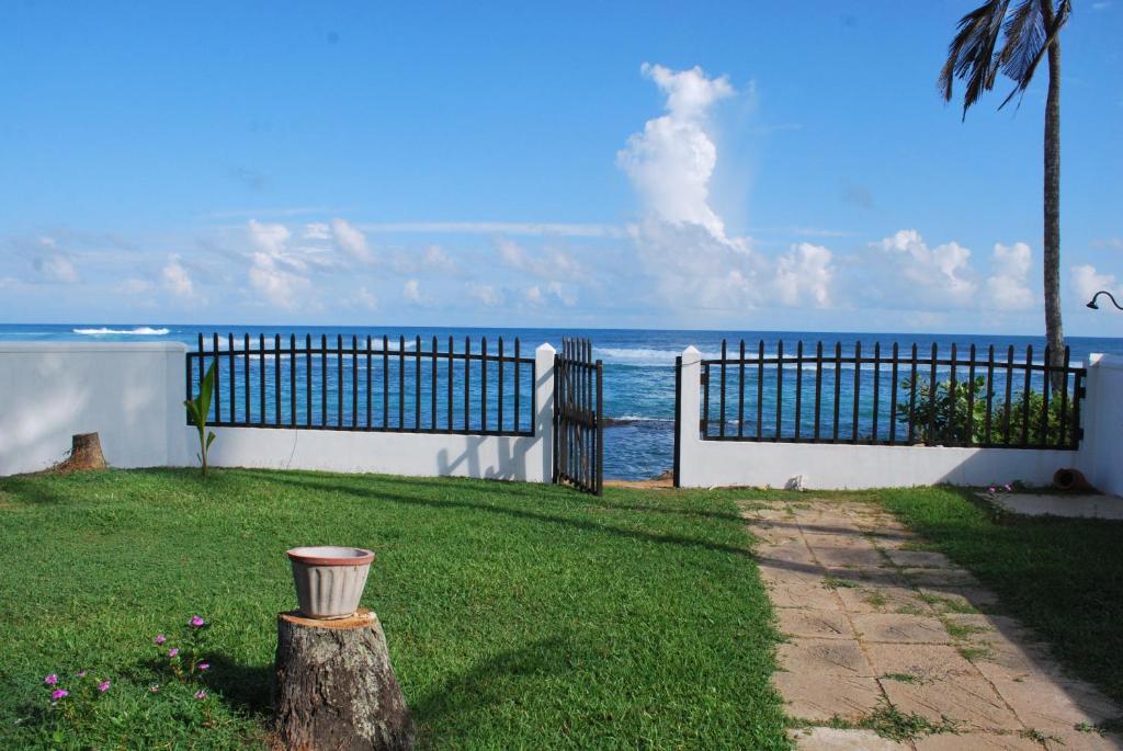 ミリッサにあるBeach Houseの塀を背景に海を背景とした庭