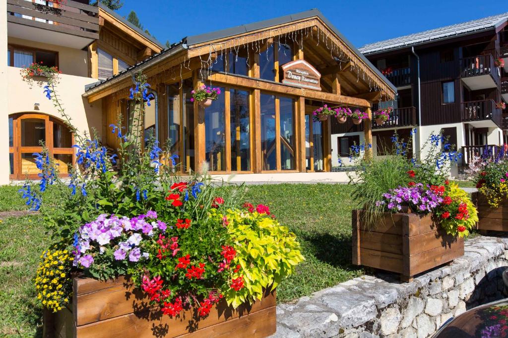 a group of flowers in front of a building at Vacancéole - Résidence Le Sappey - Doucy in La Léchère