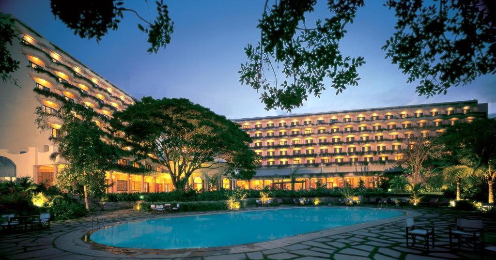 un hotel con piscina frente a un edificio en The Oberoi Bengaluru, en Bangalore