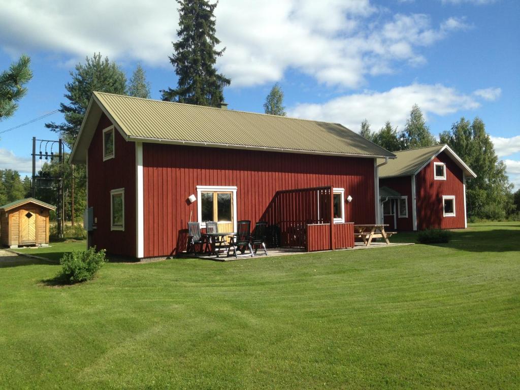 un granero rojo con una mesa y sillas en un patio en Hansjö Stugby - Mickolavägen, en Orsa