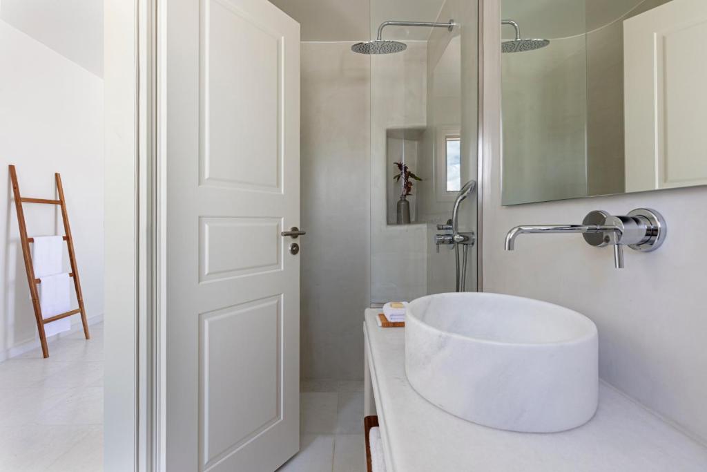 a white bathroom with a sink and a mirror at Ammothines Cycladic Suites in Naxos Chora