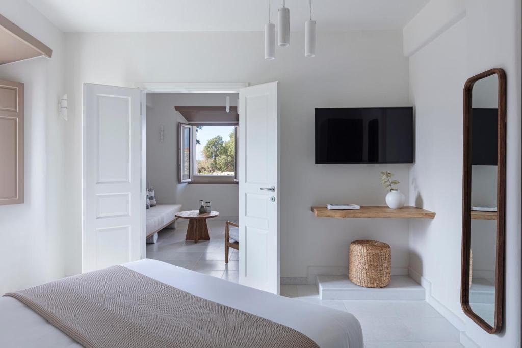 a white bedroom with a bed and a tv at Ammothines Cycladic Suites in Naxos Chora