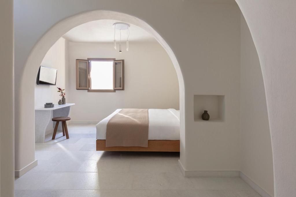 a white bedroom with a bed and a desk at Ammothines Cycladic Suites in Naxos Chora