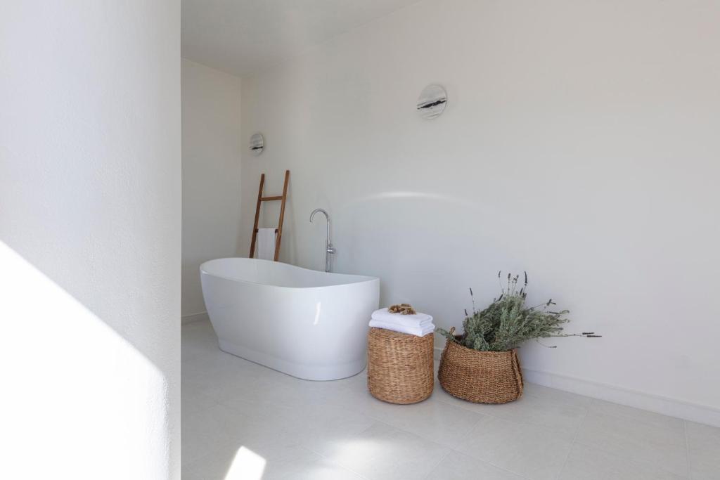 a bathroom with a white tub and a toilet at Ammothines Cycladic Suites in Naxos Chora