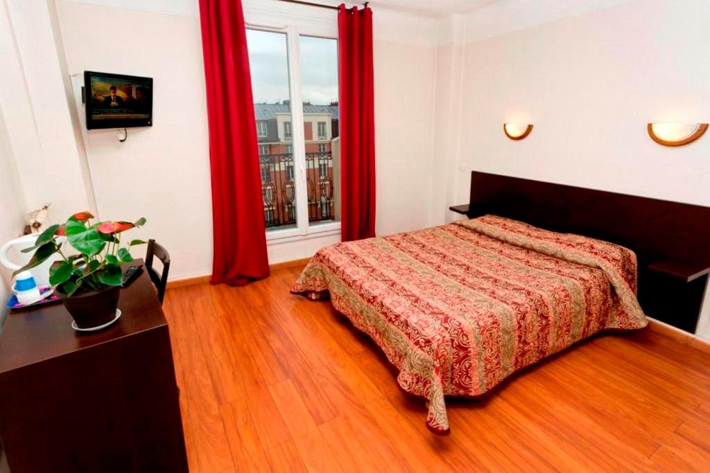 a bedroom with a bed and a window with red curtains at Hipotel Paris Printania Maraichers in Paris