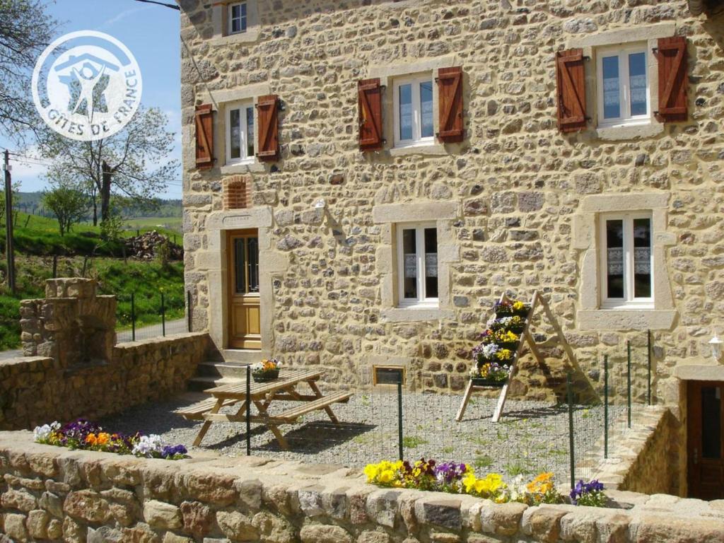 un edificio de piedra con una mesa de picnic delante de él en Gîte Saint-Bonnet-le-Courreau, 4 pièces, 8 personnes - FR-1-496-28, en Saint-Bonnet-le-Courreau