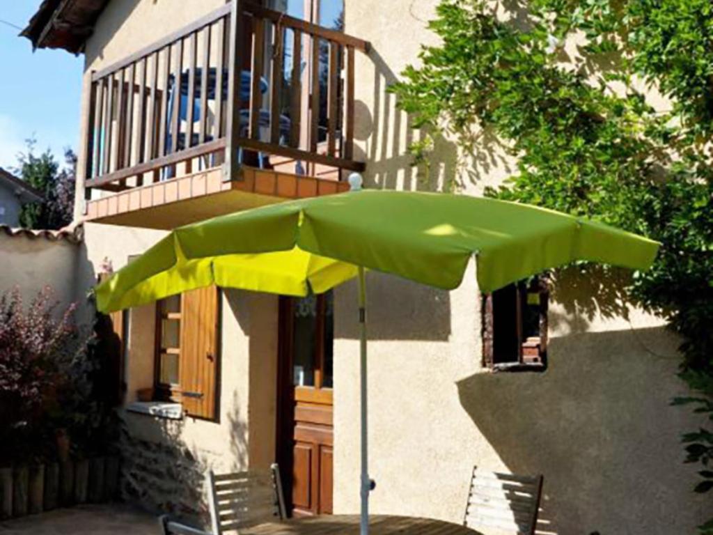 Gîte Maringes, 3 pièces, 5 personnes - FR-1-496-30 في Maringes: وجود مظلة خضراء تجلس أمام المنزل