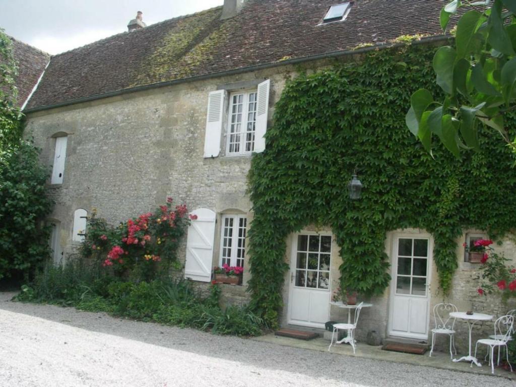 un edificio cubierto de hiedra con puertas blancas, mesas y sillas en Gîte Sarceaux, 4 pièces, 6 personnes - FR-1-497-131 en Sarceaux