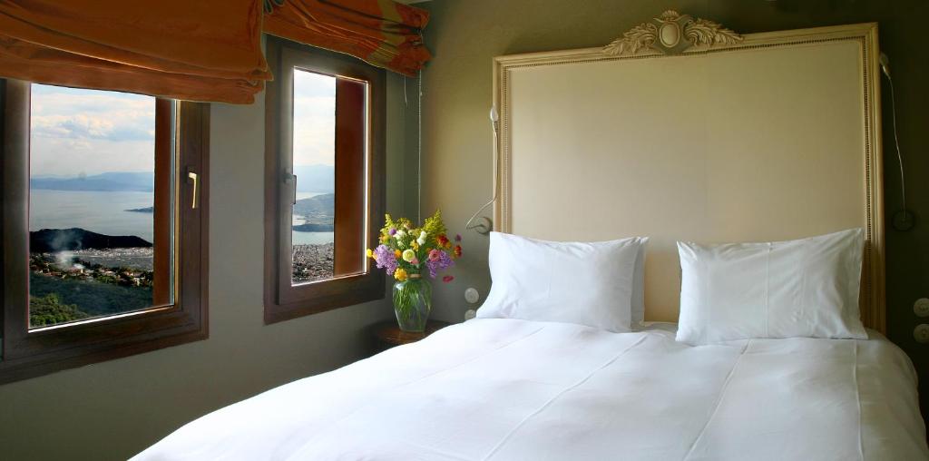 um quarto com uma cama branca e 2 janelas em Archontika Karamarlis em Makrinitsa