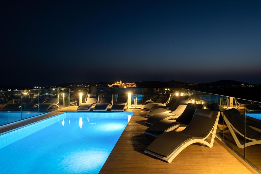 a pool on the roof of a building at night at Bliss Boutique Living in Xagħra